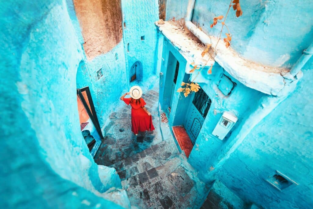 Young woman with red dress visiting the blue city Chefchaouen, Marocco